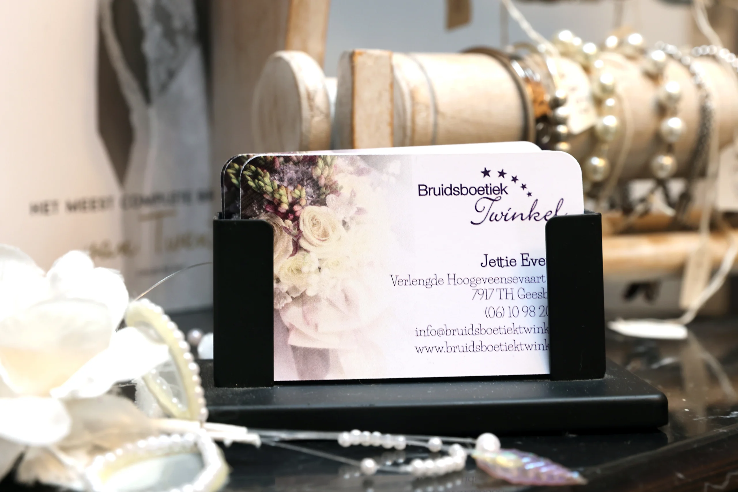 Visitekaartje van Bruidsboetiek Twinkel op een elegante display, omringd door bruidsaccessoires en sieraden, benadrukkend de aandacht voor detail en persoonlijke service.